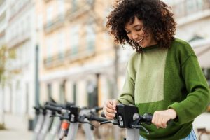 Woman standing on a city street, activating a shared electric scooter